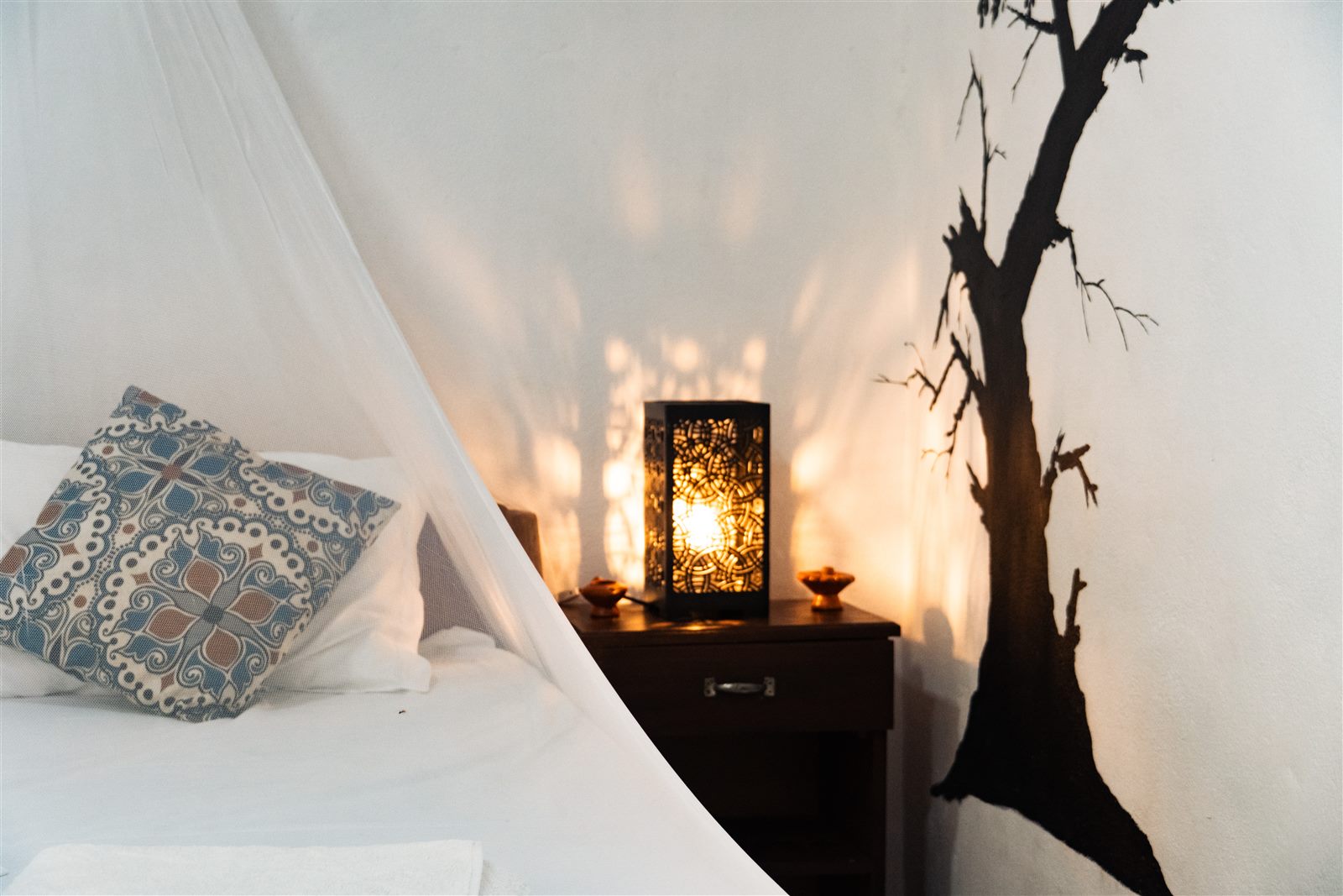 Bedside lamp and mosquito net detail in the Poolside Comfort Chalet